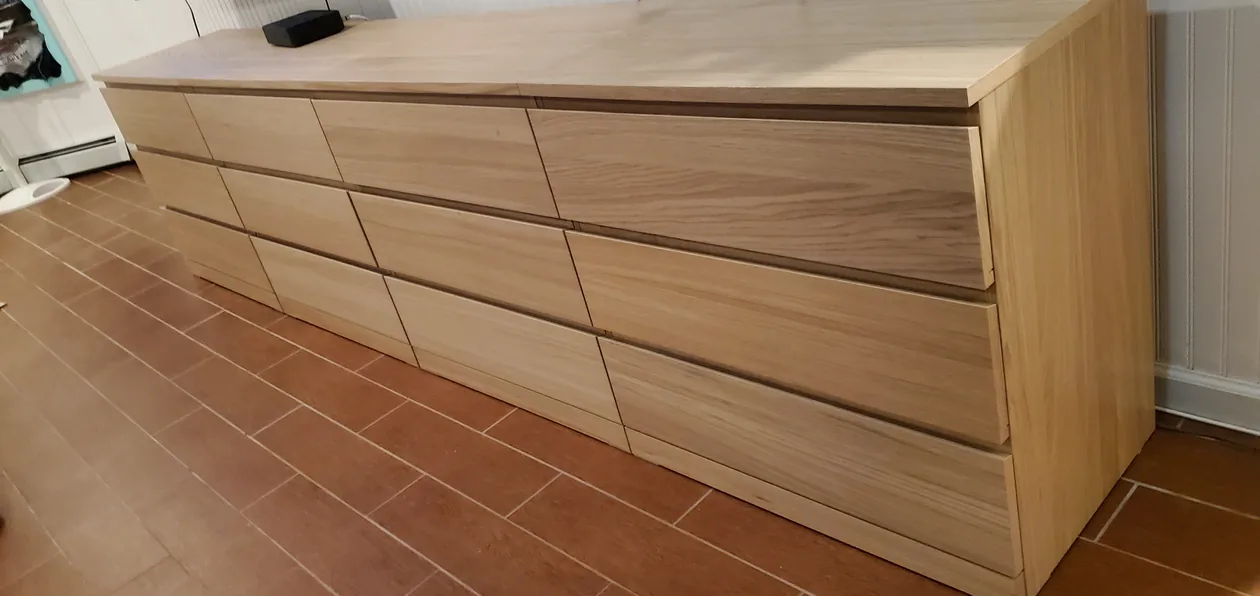 Light wood dresser with several drawers in a tiled room.
