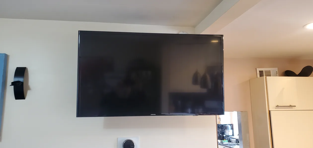 Wall-mounted television above a low cabinet in a bright room.